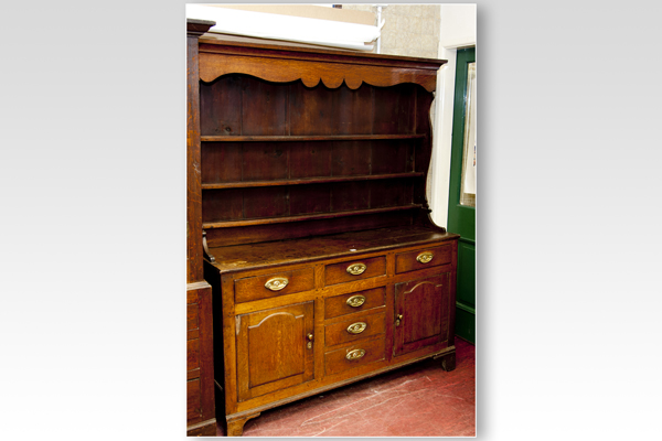 A late 18th/early 19th Century oak Welsh dresser having a three shelf rack with shaped hood and