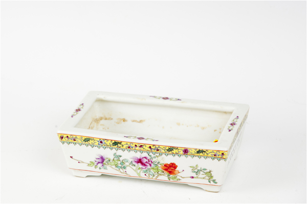 A Chinese porcelain oblong planter with floral decoration on corner supports and with red