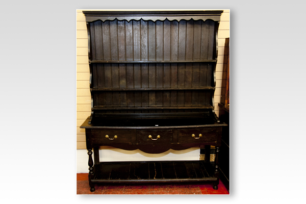 An early 20th Century dark oak dresser having a three shelf rack with shaped hood and sides over a