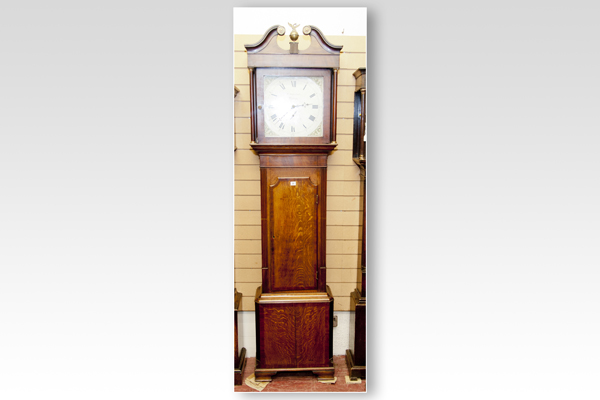 A mid 19th Century oak and mahogany longcase clock having a square hood with scrolled pediment,