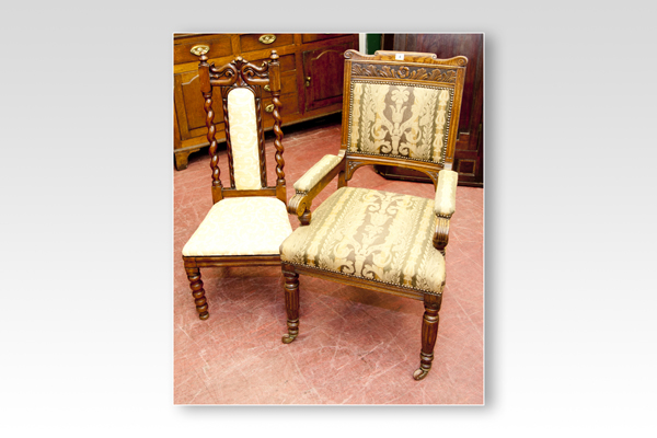 An Edwardian carved oak elbow chair with padded arms and turned and reeded supports and a rosewood