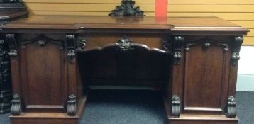 A mahogany breakfront-sideboard carved with fruit-on-the-vine and having a long central drawer