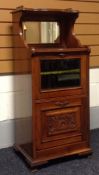 An Edwardian mahogany music-cabinet having a carved based cupboard door below a glass fall-front