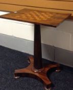 A rosewood tilt-top chequers table on a tapered and faceted column-support above a shaped base