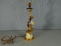 A bright ormolu electric table-lamp of naturalistic snaking form and with a seated cherub holding