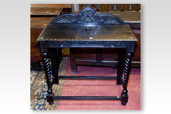 An early 20th Century ebonised oblong side table with shaped and carved back and twist corner