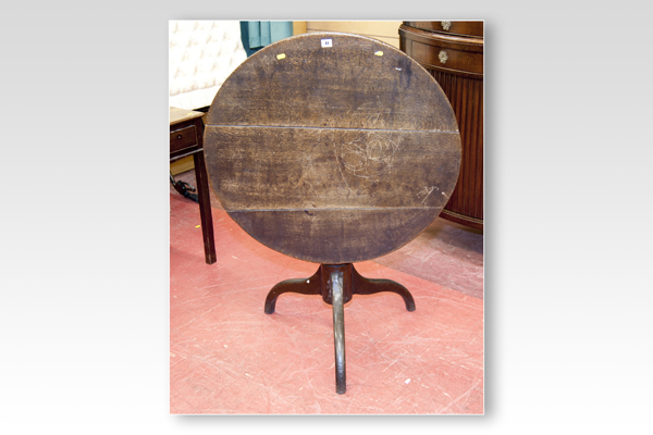 An antique oak tilt-top circular tripod table