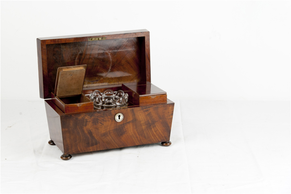 A feathered mahogany sarcophagus top oblong tea caddy having interior hinged lids with centre