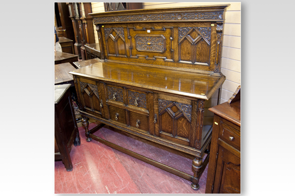 An early 20th Century polished sideboard having an intricately carved back in the Jacobean style