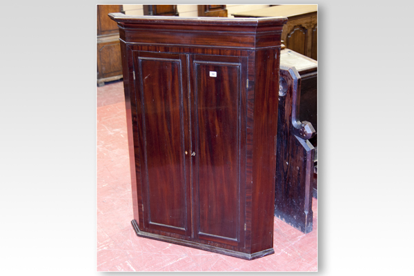 A Georgian mahogany two door hanging corner cupboard having shaped interior shelves, 35 ins (89 cms)