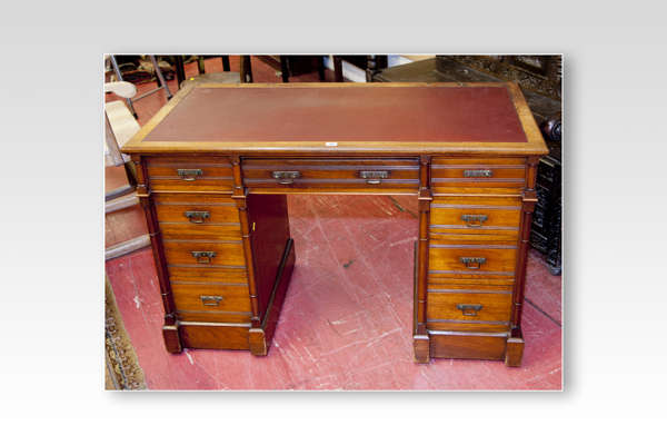 A compact Edwardian mahogany kneehole writing desk having a centre drawer with four graduated