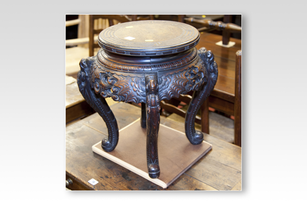 An Oriental hardwood circular jardinière stand on four mask and cabriole supports
