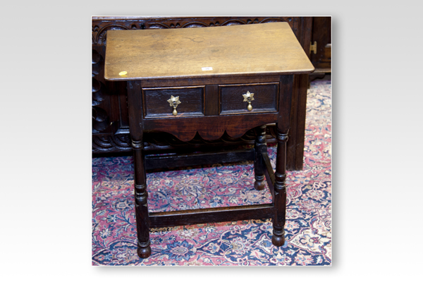 A small antique oak lowboy having two small drawers with shaped apron and turned and block supports