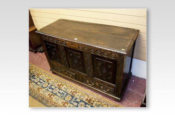 An 18th Century carved oak dower chest having a lunette narrow panel over three fielded panels and