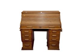 An early 20th Century light wood twin pedestal roll top desk, 46 ins wide (117 cms)