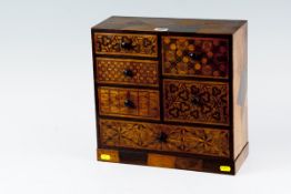 A miniature marquetry chest of drawers having three small left hand drawers, two deep box type