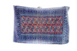 A blue and rust Eastern rug with seven row border and centre rust panel with fourteen Tekke Guls