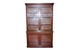 An early Victorian mahogany two piece bookcase, the upper section having two plain glass panels over