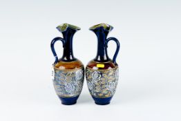 A pair of Royal Doulton narrow necked handled jugs with cobalt blue and gilt necks and a wide