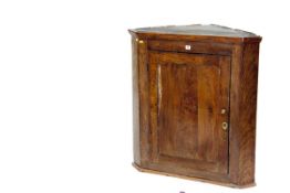 An early 19th century unrestored oak hanging corner cupboard with original shaped shelves