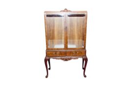 A 20th Century walnut two door display cabinet having twin doors with plain bevelled glass panels
