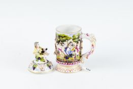 An early 20th Century Capo di Monte mug having a mask and floral handle and the whole body having
