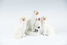 A pair of early 20th Century Staffordshire pottery seated white dogs; and a similar period oval