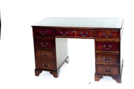 A reproduction mahogany kneehole writing desk with green tooled leather top and having a centre