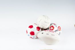 Four donated footballs bearing signatures; and a rugby ball (unsigned)