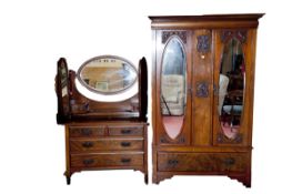 An Edwardian walnut wardrobe having two doors with oval bevelled mirrors and a drawer base, and