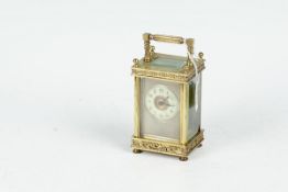 A brass encased carriage clock having bevelled panels and a white dial with eight-day striking
