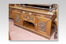 An Edwardian oak sideboard having a shaped rail back with centre carved panel and small mirrors