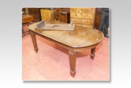 A late Edwardian polished drawleaf dining table having bowed ends, a wide centre leaf and square