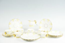 An Aynsley twenty-one piece white ground yellow and gilt decorated tea set, each cup and the cream