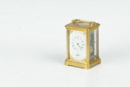 A brass encased carriage clock with bevelled glass panels, having a white dial with Roman numerals
