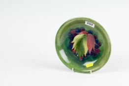 A circular Moorcroft green ground `Leaf and Berry` shallow dish, 7.25 ins (19 cms) diameter