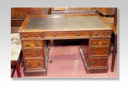 A Victorian mahogany kneehole desk having a Rexine top with a long narrow central drawer with four