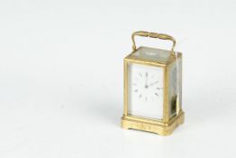 A brass encased carriage clock with leaf chased brasswork, bevelled glass panels, a white dial