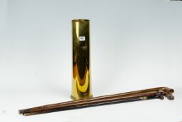 A large brass shell case with three rustic walking sticks