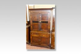 An early 19th Century Welsh oak two piece bread and cheese cupboard, the upper section having twin