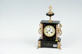 A black slate mantel clock with pink and orange marble corners, ormolu scrolled side handles and