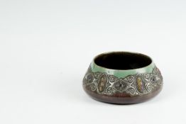 A circular art pottery shallow bowl decorated with a band of pewter and semi-precious stones, 8