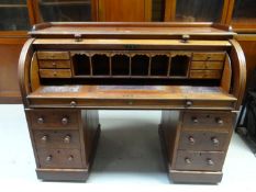A good 19th Century mahogany roll top desk having a solid cylindrical cover, two banks of three