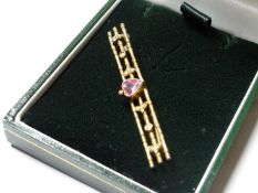 A nine carat gold triple bar brooch with centre heart shaped pink stone and flanking seed pearls.