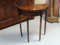 A small late 18th/early 19th Century mahogany demi-lune foldover games table with baize lined