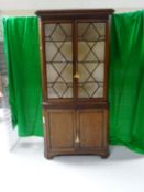 An early 19th Century Welsh oak standing corner cupboard, the flared cornice above a mahogany frieze
