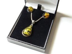 A silver box link chain with three amber style pendants, two circle, one pear drop.