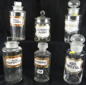Six large pharmaceutical jars, each with various labels and all but one having a stopper, tallest 11