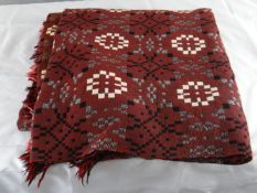 A good Welsh wool blanket in a rust colour with black, white and grey geometric patterns.