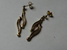 A pair of nine carat gold shaped and curved long earrings.